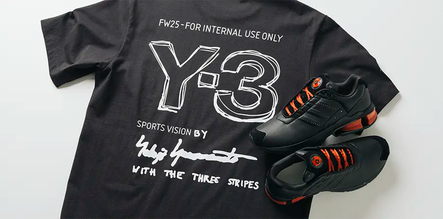 A black T-shirt with white Y-3 branding and signature print, next to a pair of black Y-3 A3 Control sneakers with orange accents and laces.