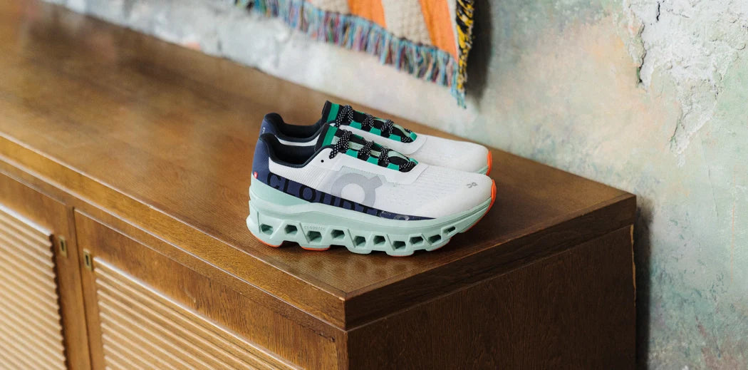 On Running Cloudmonster sneakers placed on top of a dresser