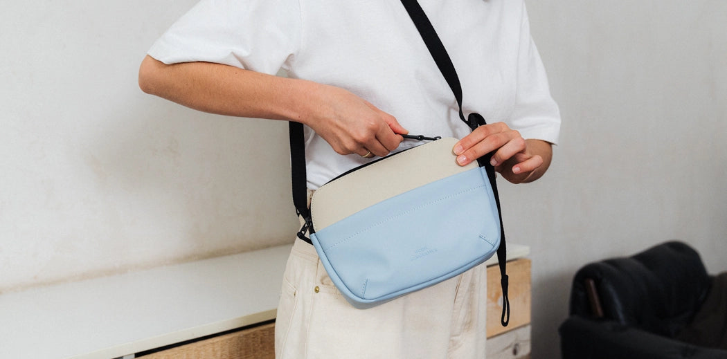 Woman holding a Ucon Acrobatics pink purse in front of car.