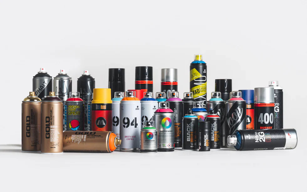 A variety of colorful spray paint cans of different brands and sizes are arranged on a white surface. The scene conveys creativity and artistic potential.