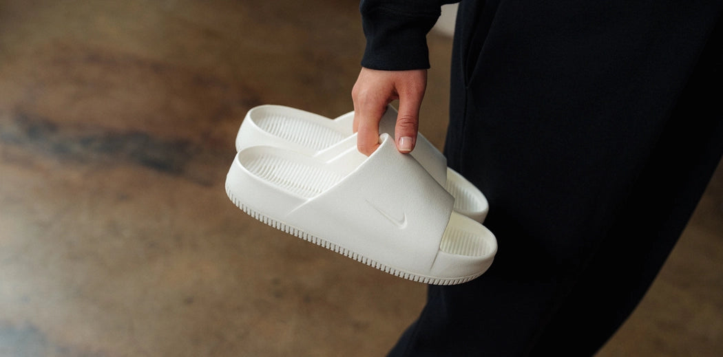 Stylish green slides sneakers on a wooden floor.