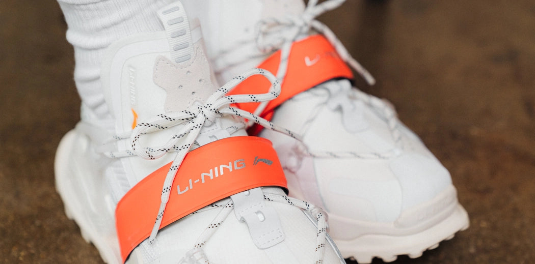 Li-Ning sneakers in white and black, three pairs on wood floor.