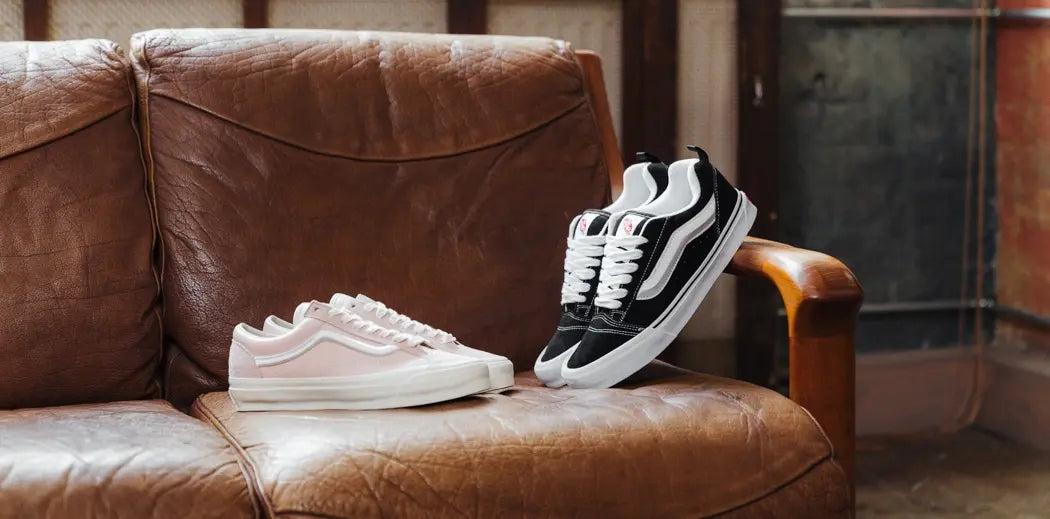 Man in black Vans Oldskool sneakers tying his shoelaces.