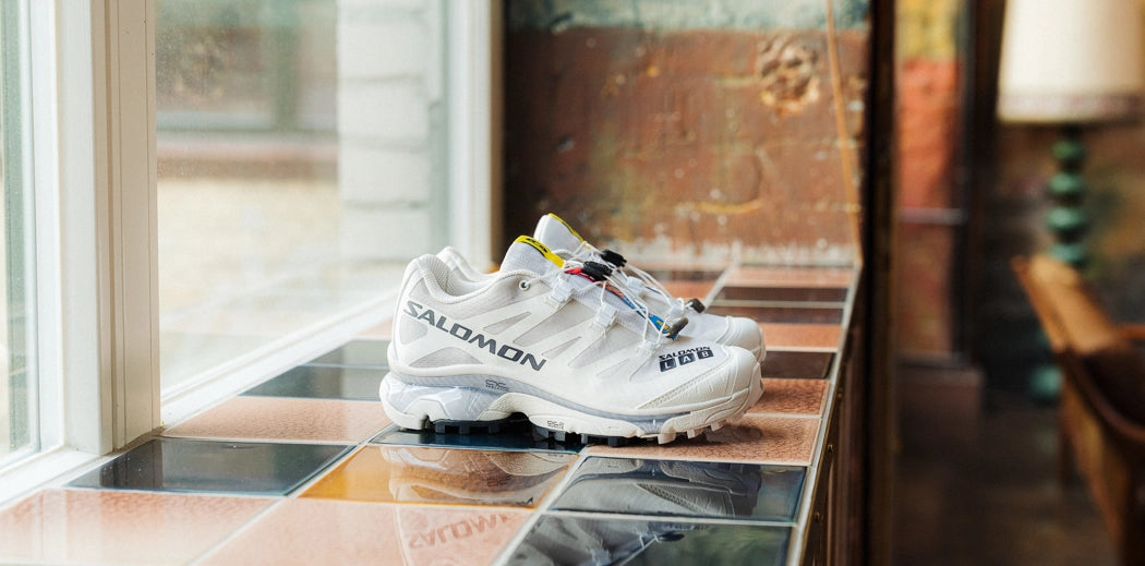 Stylish white sneakers for women placed on a wooden table.