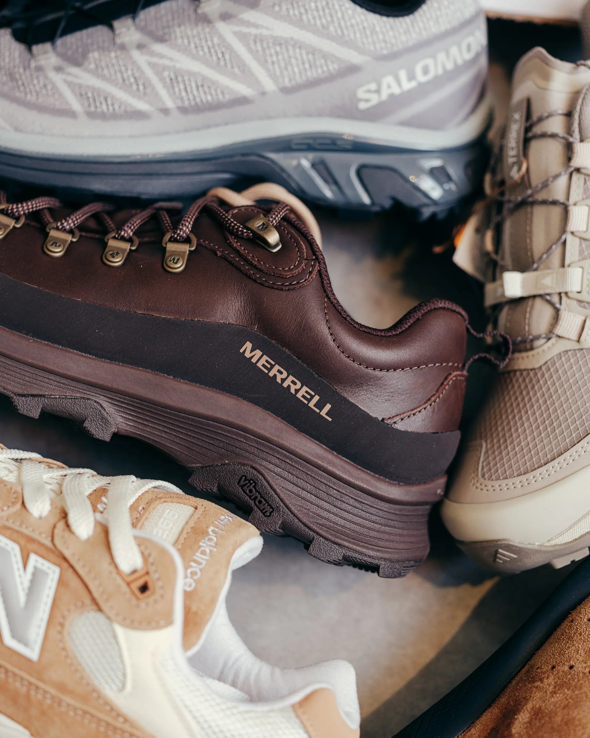 Close-up of four hiking shoes: brown leather, beige mesh, gray knit, and tan suede. Brands visible, representing rugged, outdoor adventure gear.
