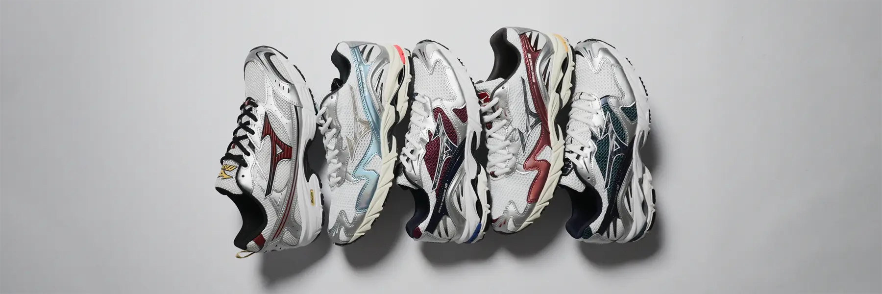 Five stylish athletic sneakers from Mizuno are lined up horizontally against a light gray background. Each shoe features unique color accents on a primarily white base.