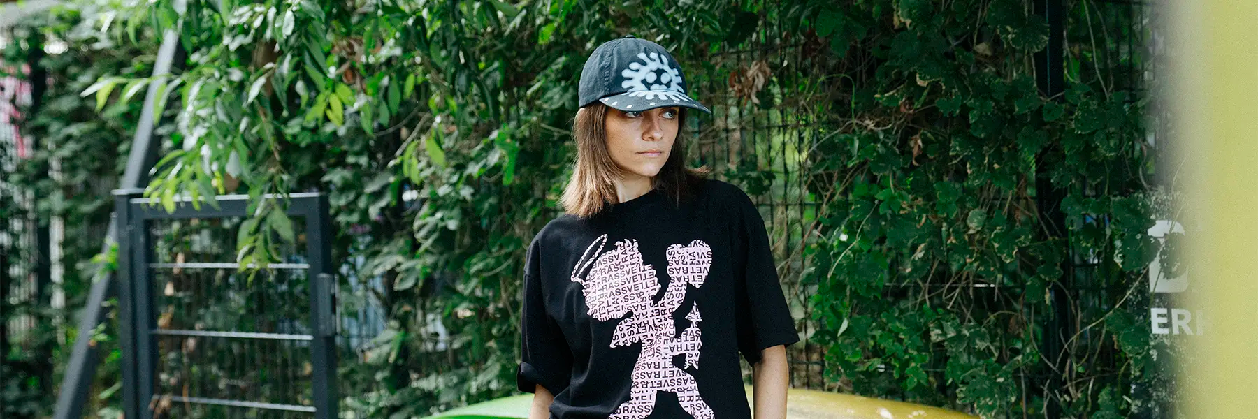Model with Base Cap and T-Shirt from Rassvet standing in front of green leaves