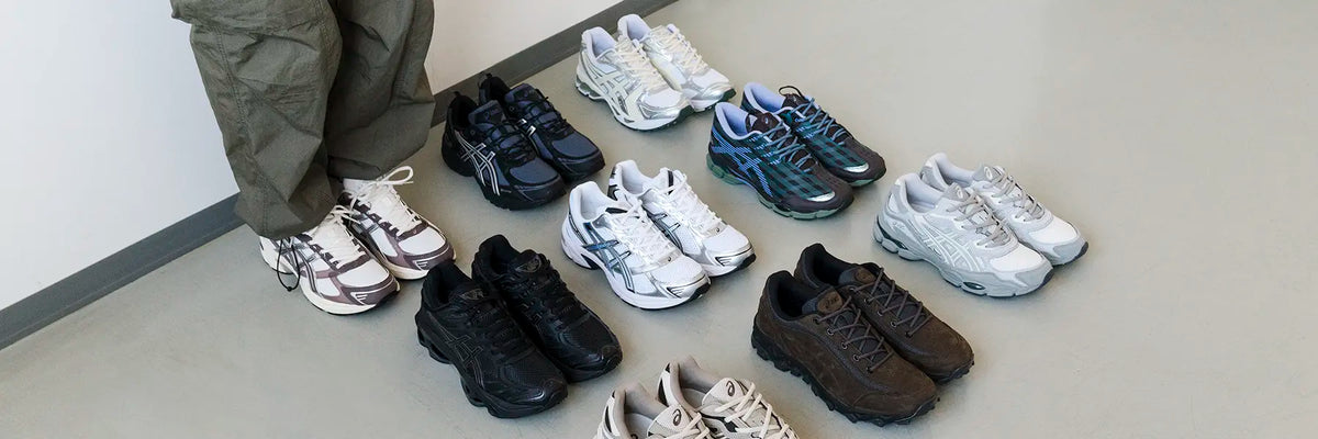 Person wearing olive pants standing next to multiple pairs of Asics Y2K Sneaker athletic shoes arranged on the floor