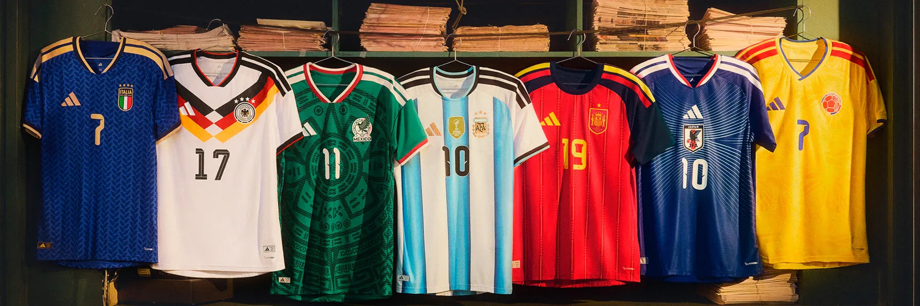 Seven adidas Football jerseys hang in a row, featuring various national team colors and designs. The scene conveys a sense of international sports unity. Germany, Mexico, Argentina, Italia, Spain, Japan