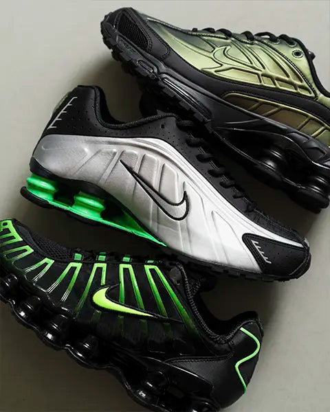Three pairs of Nike Shox sneakers stacked: silver with green accents, black with neon green, and a sleek black and metallic green design.
